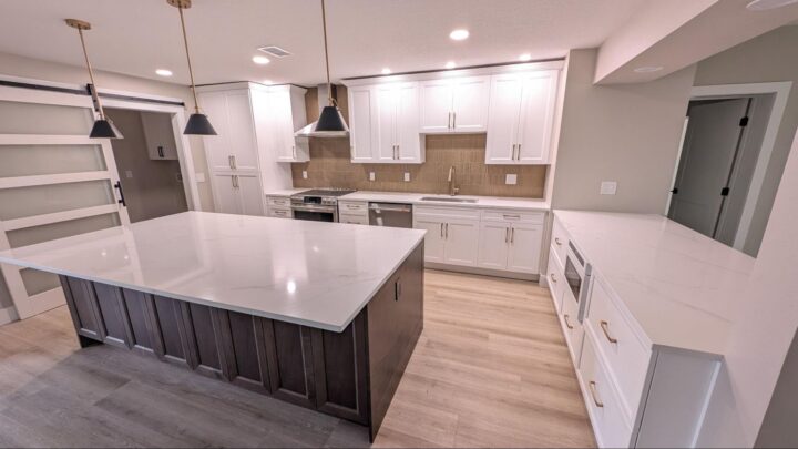 Modern white kitchen remodel with large island, custom cabinetry, pendant lighting, and quartz countertops